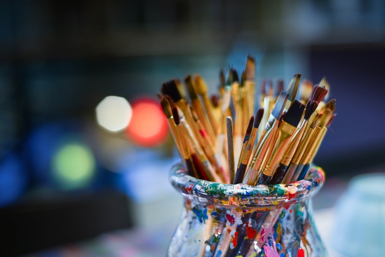 Des jolis crayons et pinceaux dans un pot joliment taché de peinture